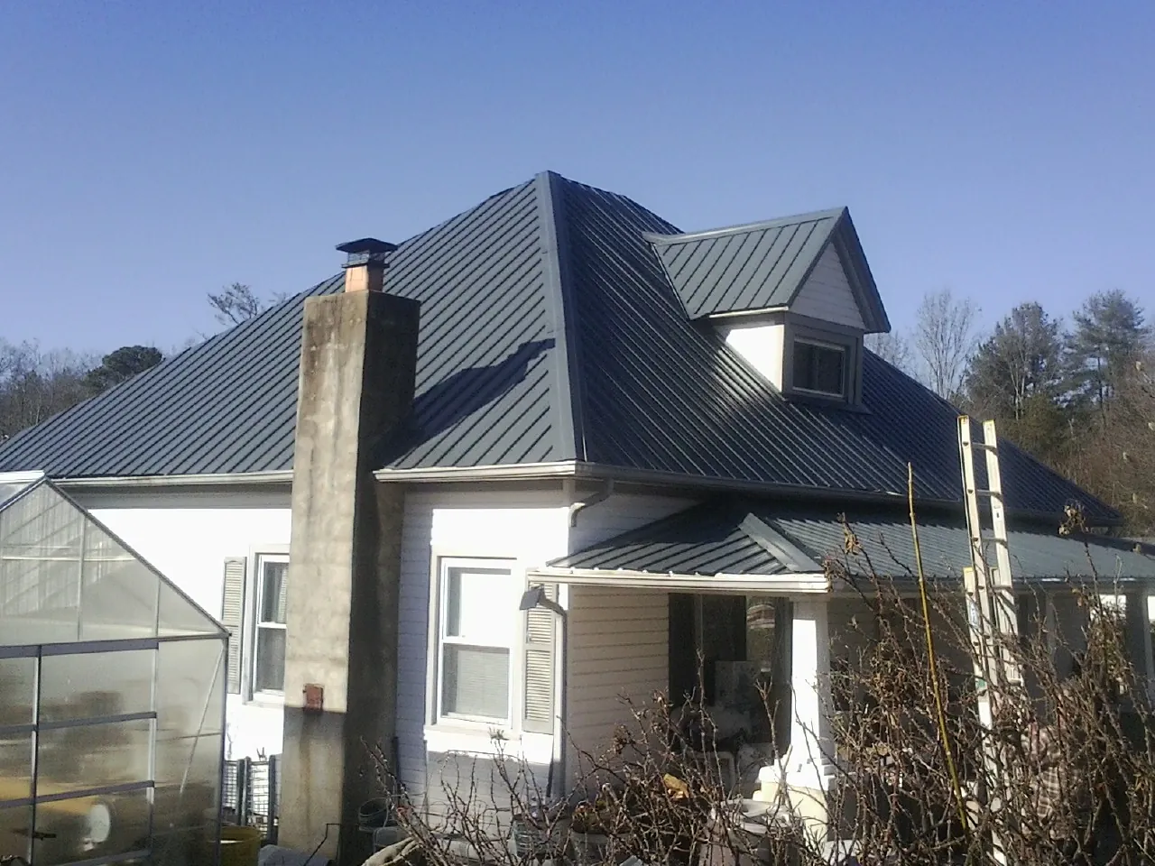 Dark blue standing seam metal roof on a white farmhouse with dormer — Slate & Tile Roof Repair by Roofing Brothers in Cave City