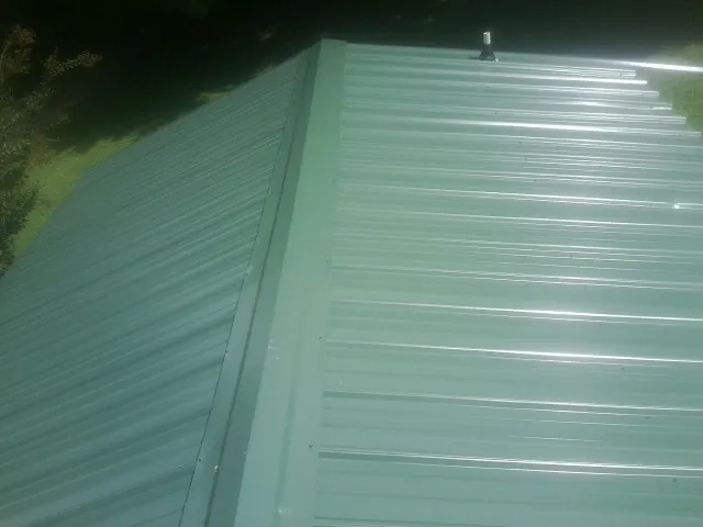 New green metal panels meeting at the ridge of a roof — Flat Roof Repair work by our crew in Cave City