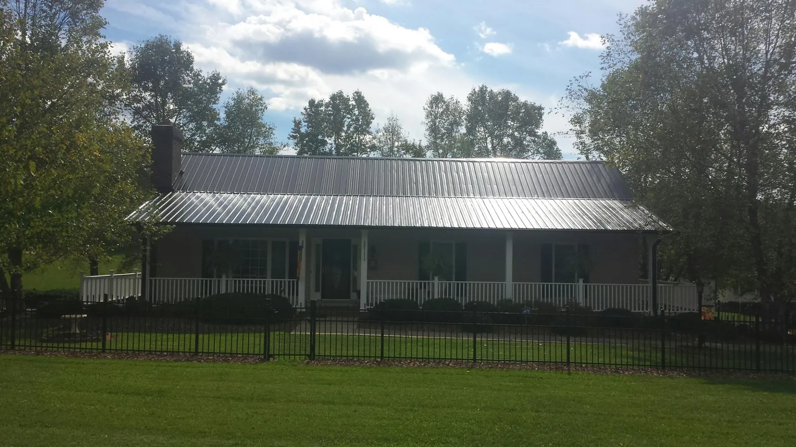 Gray metal roof on a brick ranch with a full width front porch — Gutter Guard Installation work by our crew in Cave City