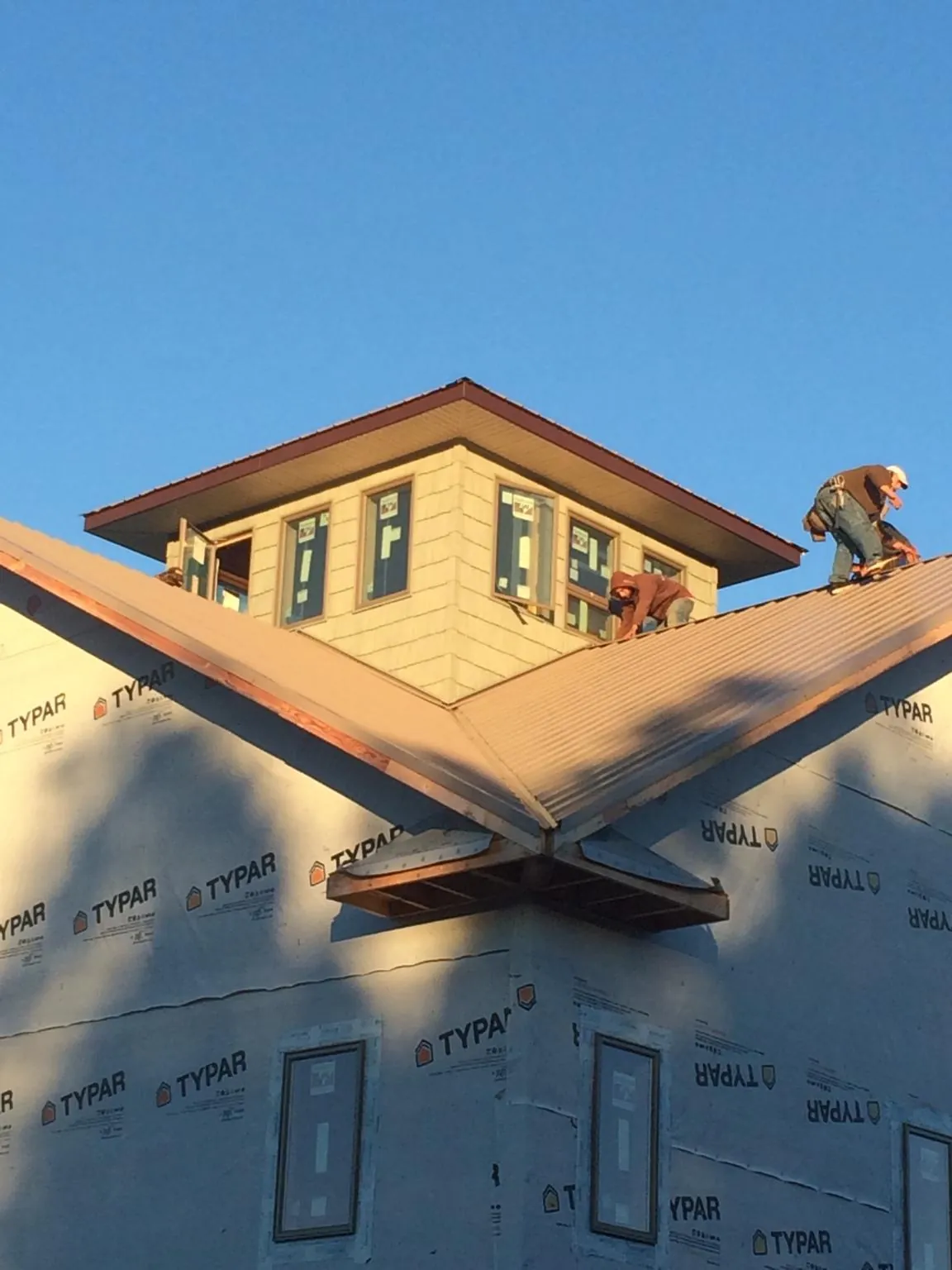 Roofers working around a rooftop cupola on a new metal roof at sunset — Roof Waterproofing in Cave City by Roofing Brothers